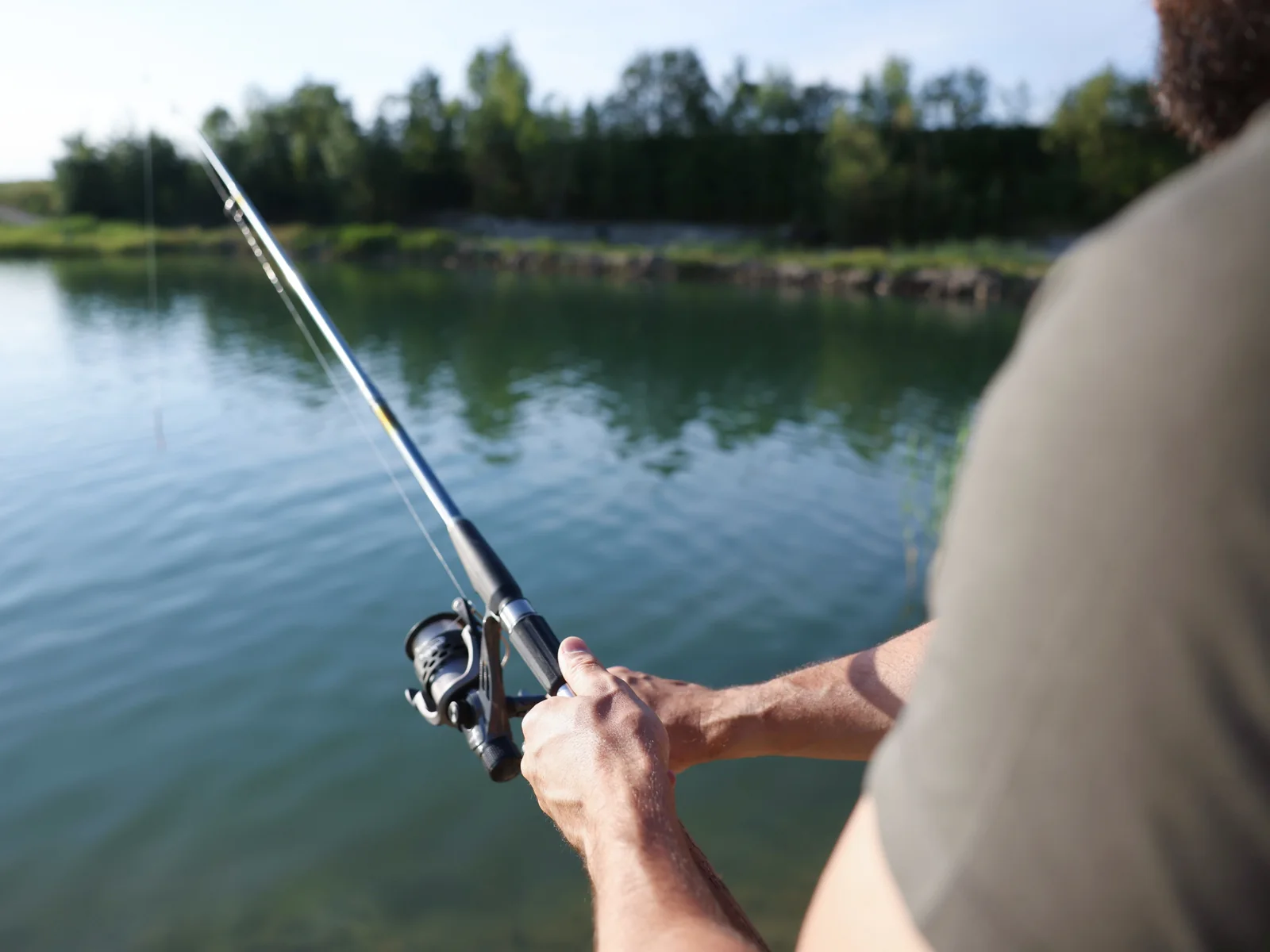 Caña de spinning apuntando a un embalse en calma durante una jornada de pesca